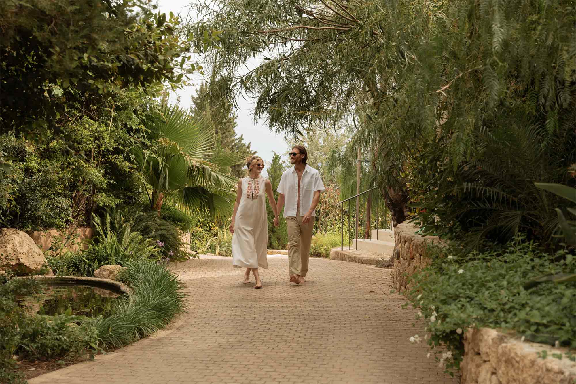 man and woman enjoying walk on hotel pathway surrounded by trees