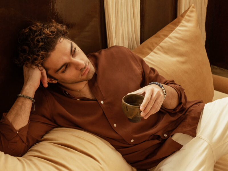 Guy sitting on a bed wearing handmade Greek bracelet