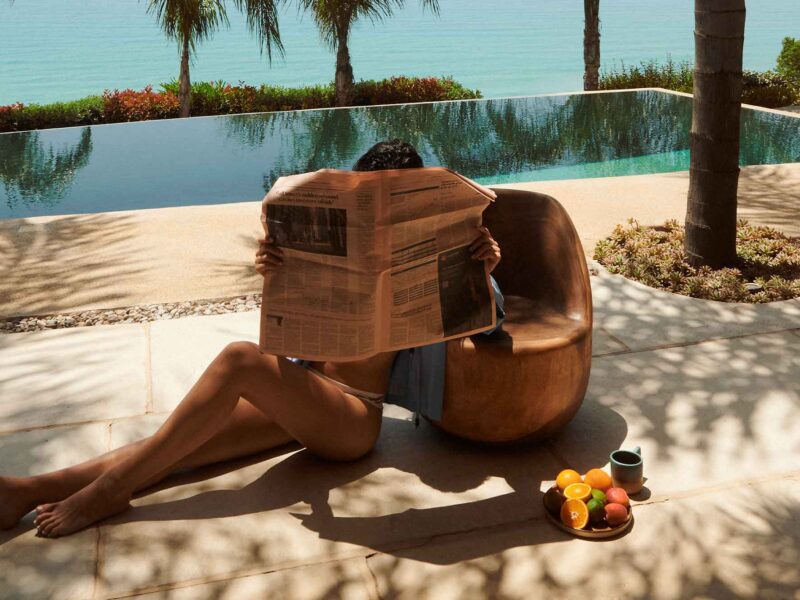 JOMO woman with newspaper relaxing by pool