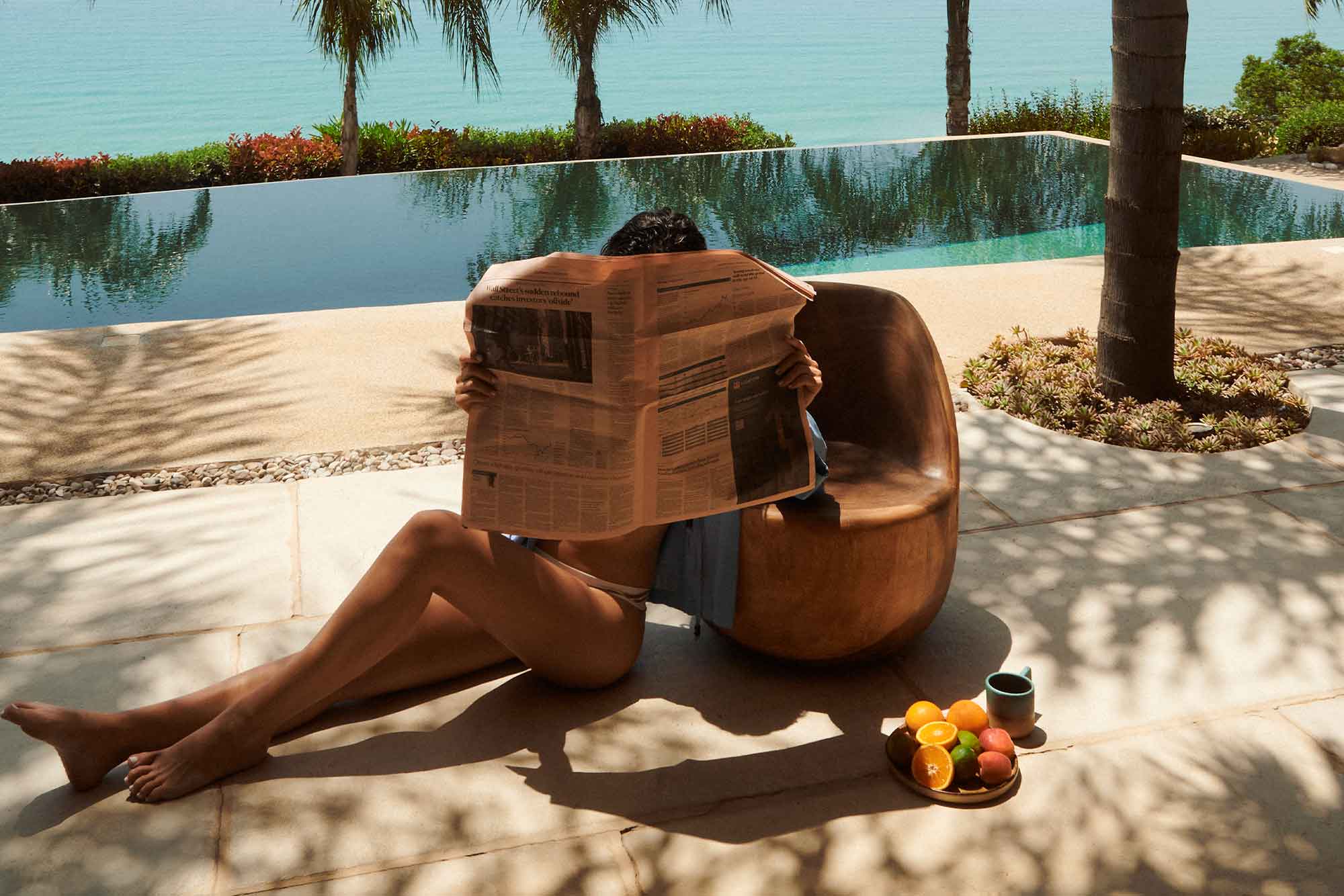 JOMO woman with newspaper relaxing by pool
